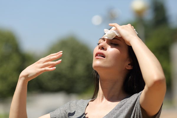 Woman wiping sweat off forehead