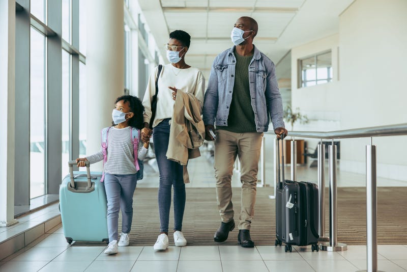 Family walking through airport, wearing masks.