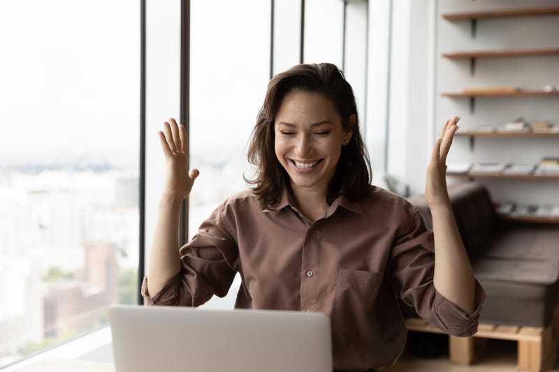 Woman looking happily at computer screen.