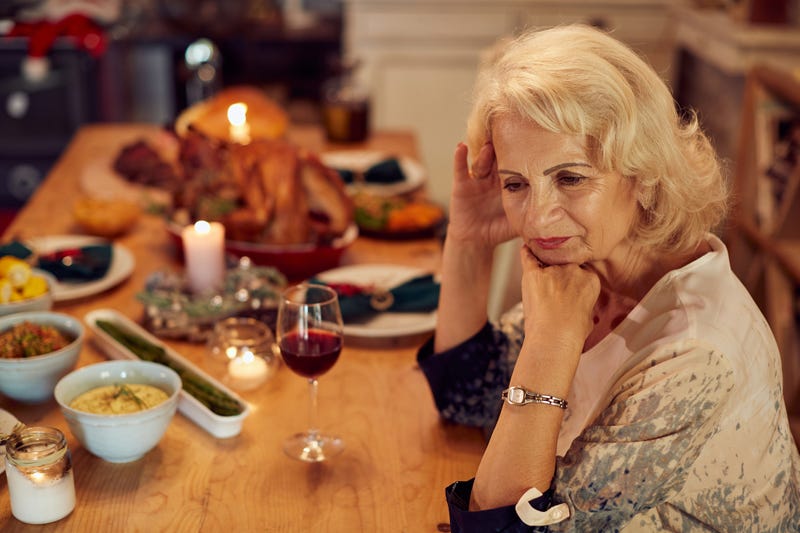 Woman feeling lonely and missing her family at dining table on Thanksgiving.