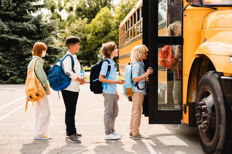 students standing in line waiting to board school bus