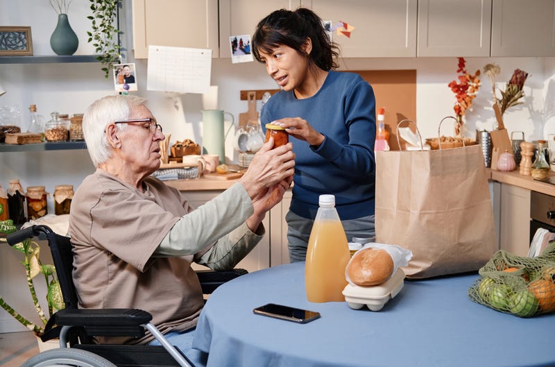 young woman helping an old man unpack groceries