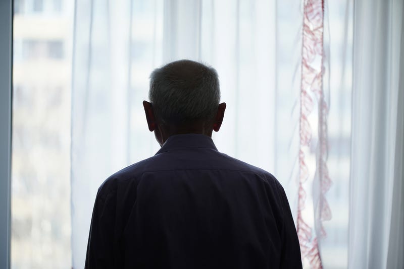 Man looking sadly out of a window.