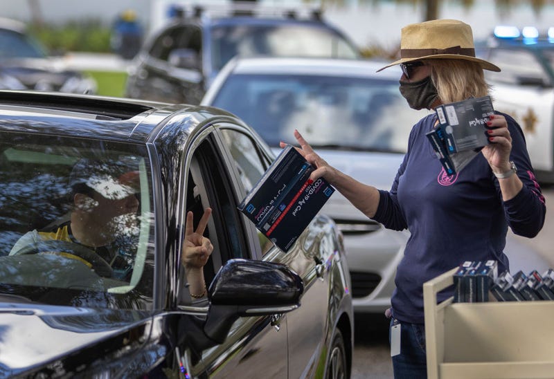Cathy Feller hands out free COVID-19 at-home rapid test kits during a drive-thru event at the Hollywood library on December 30, 2021 in Hollywood, Florida.