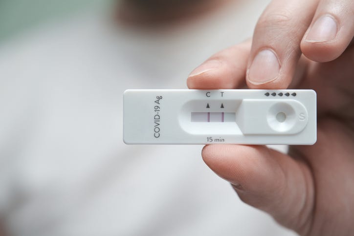 Close-up of a hand holding a positive antigen test for COVID-19