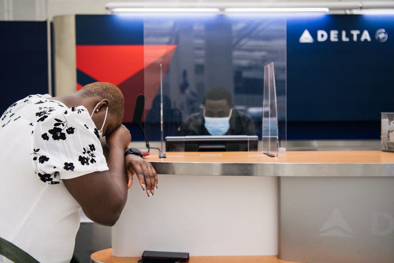 A customer rests their head down while speaking with a Delta Airlines employee at the George Bush Intercontinental Airport on January 13, 2022 in Houston, Texas. Due to the COVID-19 pandemic, Delta Airlines cancelled thousands of flights and lost $408 million in the final quarter of 2021. Delta has predicted that it will suffer one more quarterly loss before travel picks up in the spring and summer. (Photo by Brandon Bell/Getty Images)
