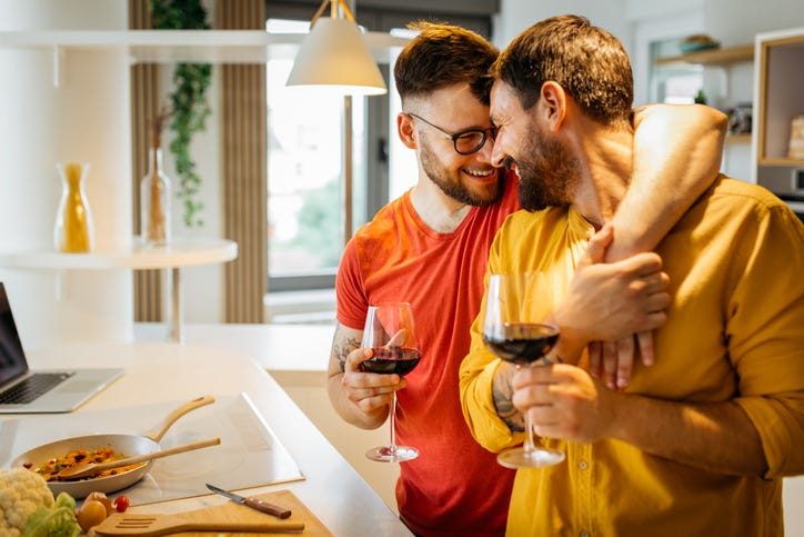 A couple drinks wine while cooking together
