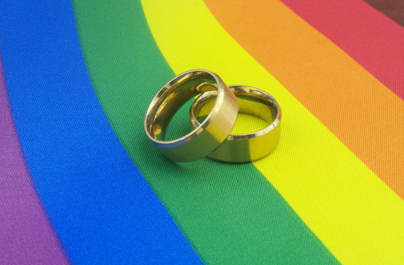 Two wedding bands on a rainbow flag.