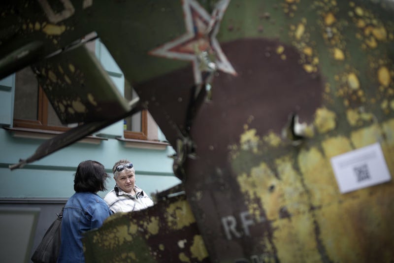 Women chat on the street next to the remnants of a destroyed Russian fighter jet which is part of a display of Russian military hardware that has been put on the street for public viewing in central Kyiv on May 17, 2022 in Kyiv, Ukraine.