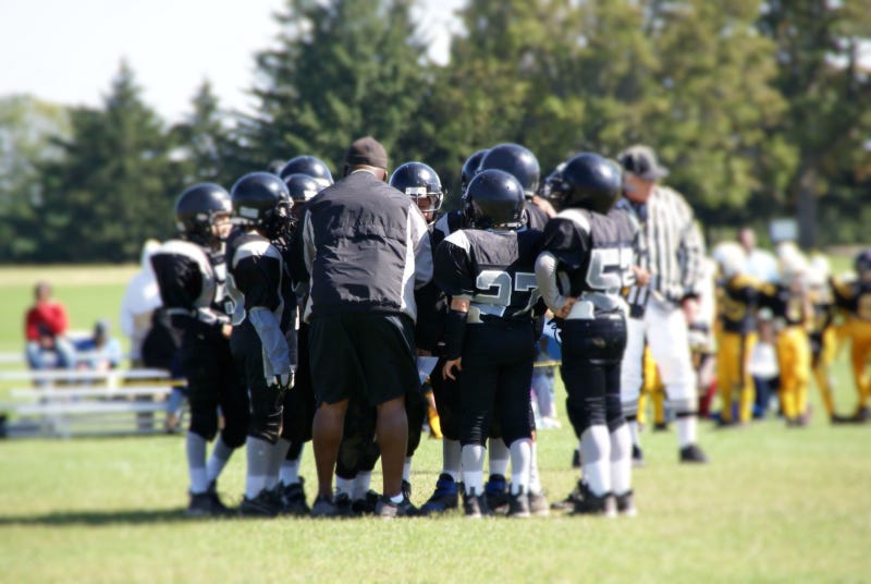 Youth football team huddles on the field.