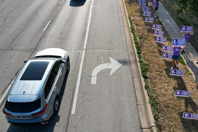 In this aerial view, supporters of the Vote Yes to a Constitutional Amendment on Abortion hold up signs along 135th Street on August 01, 2022 in Olathe, Kansas. On August 2, voters will vote on whether or not to remove protection for abortion from the state constitution. (Photo by Kyle Rivas/Getty Images)