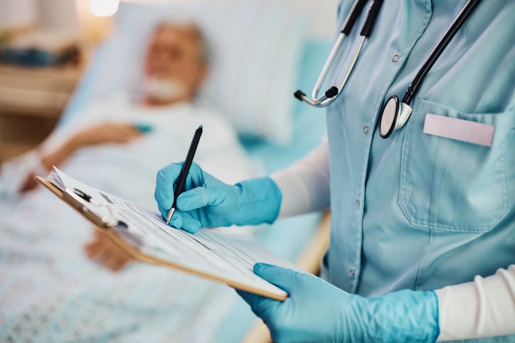 Close up of nurse writing data into medical record of hospitalized patient