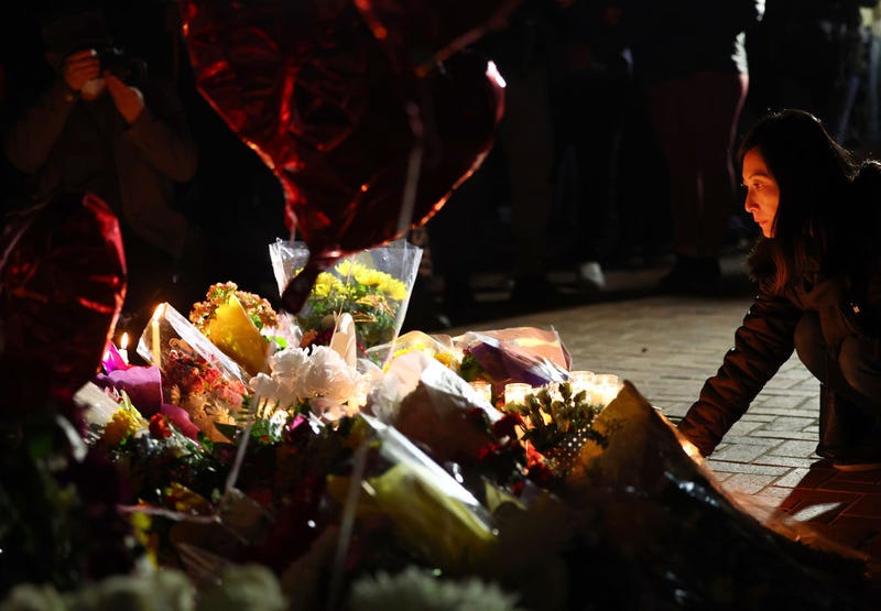 A person kneels at a candlelight vigil for victims of a deadly mass shooting at a ballroom dance studio on January 23, 2023 in Monterey Park, California.