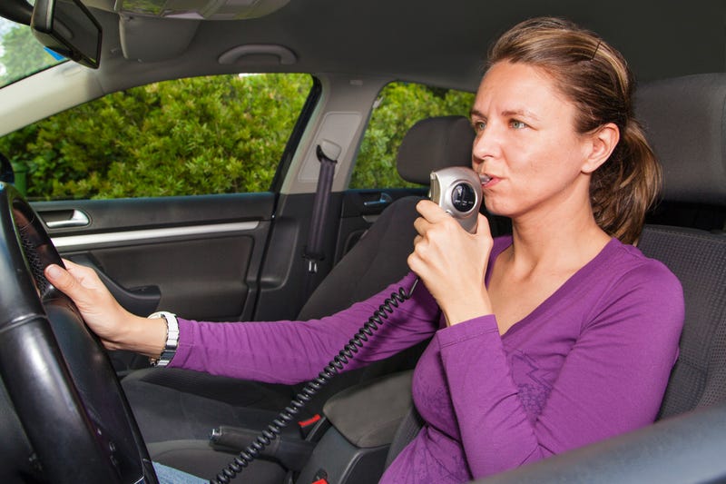 Woman blowing into a breathalyzer in her car