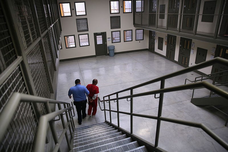 A guard escorts an immigrant detainee from his 'segregation cell' back into the general population at the Adelanto Detention Facility