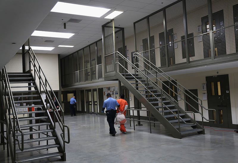 A guard escorts an immigrant detainee from his 'segregation cell' back into the general population at the Adelanto Detention Facility