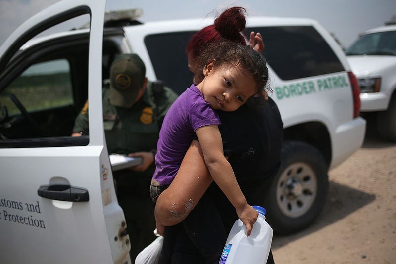 A mother and child, 3, from El Salvador await transport to a processing center for undocumented immigrants after they crossed the Rio Grande into the United States on July 24, 2014 in Mission, Texas.