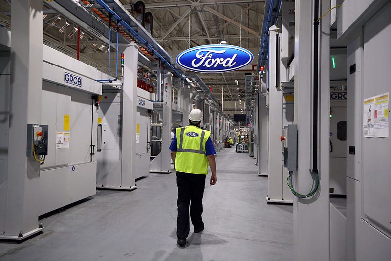 An employee walks past a Ford logo