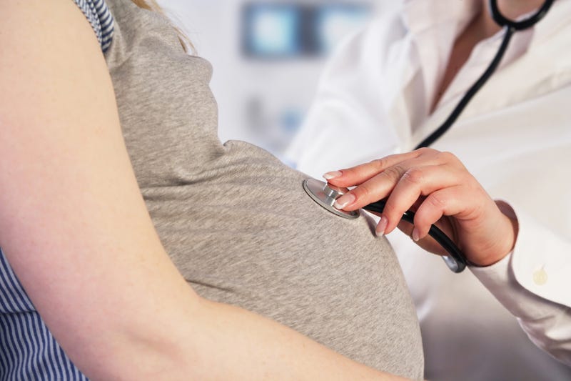 A doctor checks a baby's heartbeat in a pregnant woman