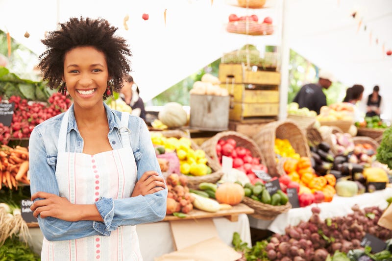 Woman standing near produce with apron on at a Farmer's Market