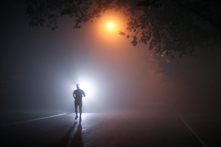 Runner at night in fog.