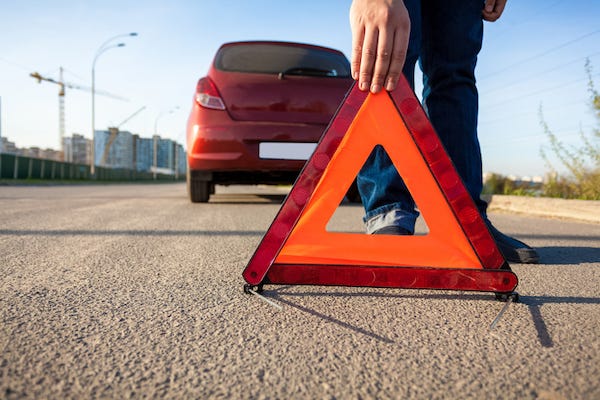 Man putting triangle warning sign on road