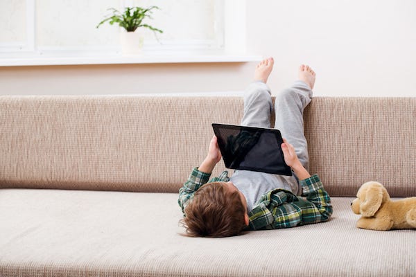 Boy playing with digital tablet while sitting on the sofa