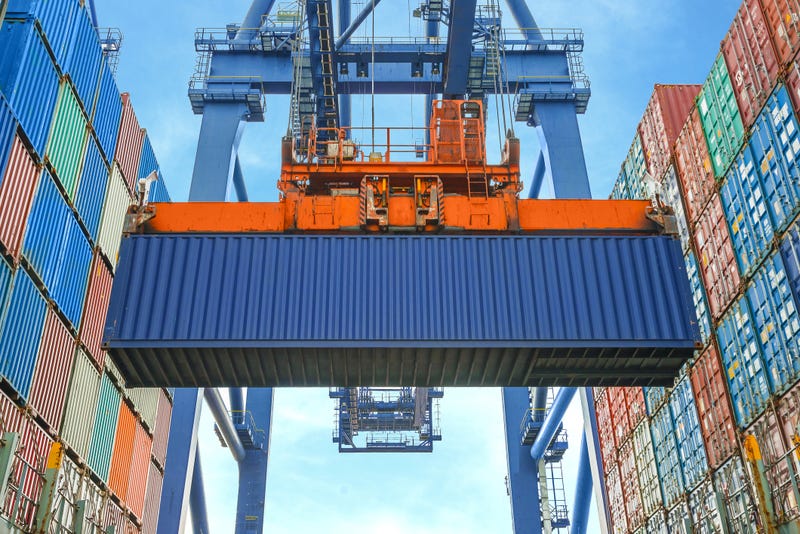 A shipping container lifted by a crane at a port