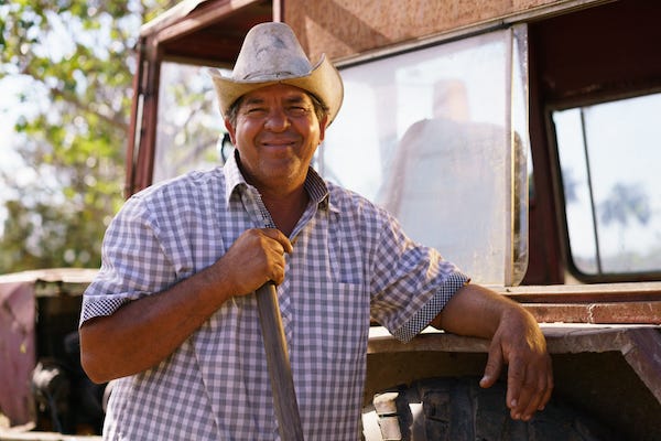 Happy farmer leaning on tractor