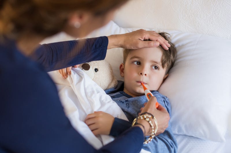 Sick boy with thermometer laying in bed