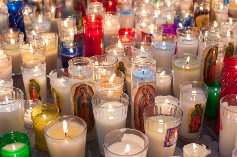 Hundreds of glass vase religious candles featuring the Virgin Mary as Our Lady of Guadalupe lit on church floor in Mexico