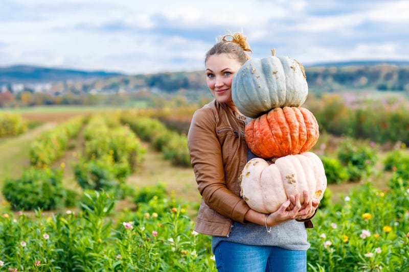 woman picking up pumpkins for halloween