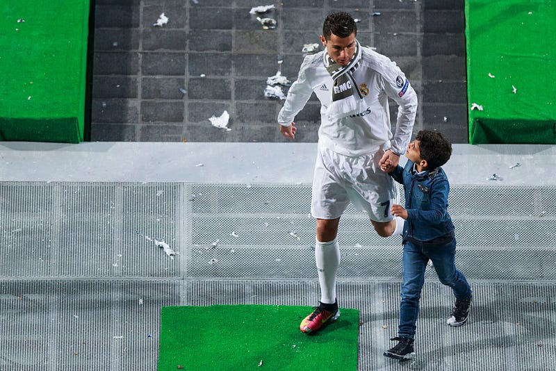 Cristiano Ronaldo (L) of Real Madrid CF leaves the pitch with his son Cristiano Ronaldo Jr. (R) after the celebration with their fans at Santiago Bernabeu Stadium the day after winning the UEFA Champions League Final match against Club Atletico de Madrid on May 29, 2016 in Madrid, Spain.