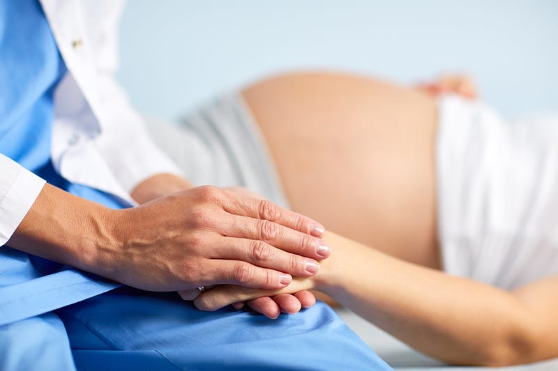 Nurse holding pregnant woman's hand.