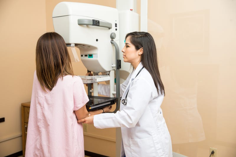 Doctor helping patient get a mammogram - stock photo