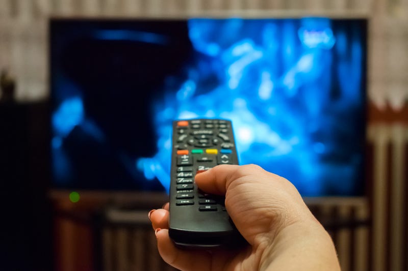 hand holding remote control pointed at television