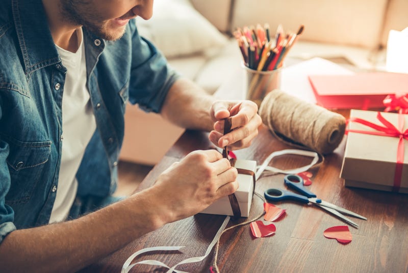 A man adds a ribbon to a wrapped gift