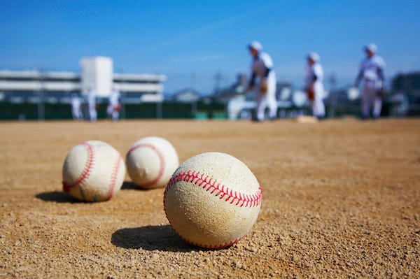 Baseballs resting on dirt in front of baseball team