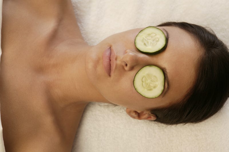 A woman lies on a blanket with cucumber slices over her eyes