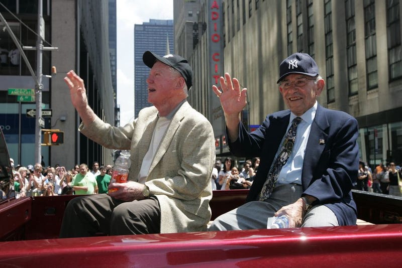 Whitey Ford and Yogi Berra sit in the back of a car during a parade