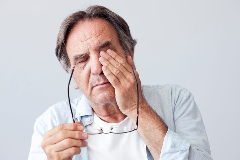 An old man rubs his eyes