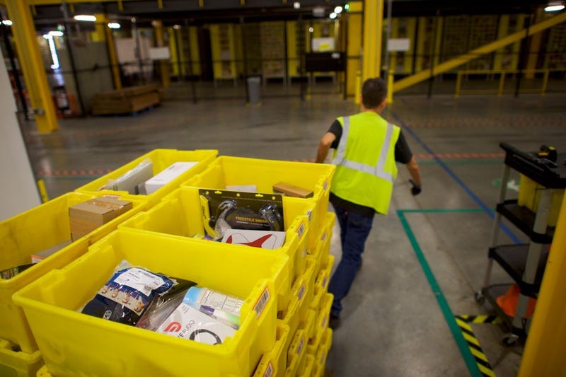 An Amazon employee hauls a fork lift of boxes at an Amazon Fulfillment Center