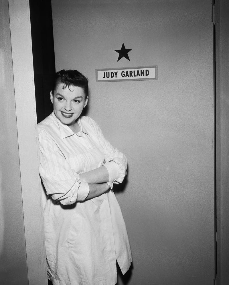 American actress and singer Judy Garland (1922 - 1969) stands outside her dressing room door backstage on the set of the live performance anthology series 'Ford Star Jubilee,' New York, August 19, 1955. The episode, titled 'The Judy Garland Special,' aired on September 24, 1955.