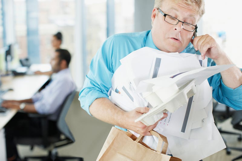 Businessman talking on phone holding paperwork and coffee