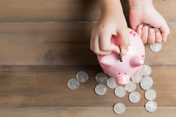 Hand putting coins in a piggy bank