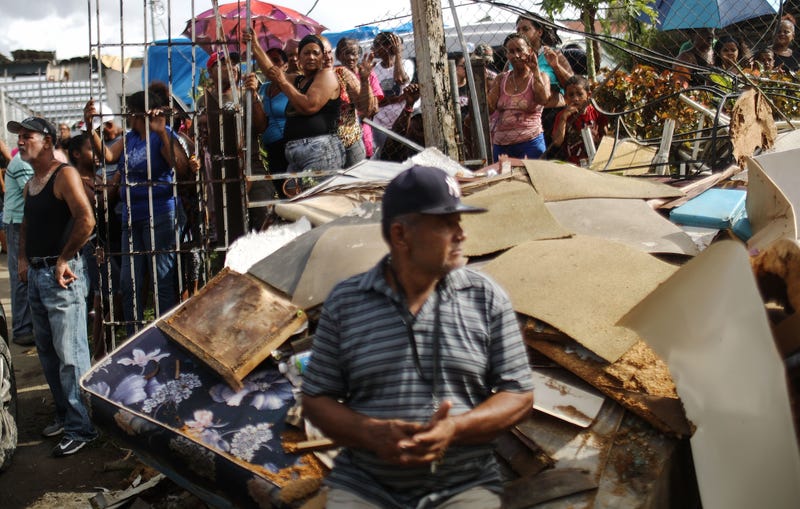 Residents wait as U.S. soldiers unload food and water, provided by FEMA, in a neighborhood still without grid electricity or running water on October 17, 2017 in San Isidro, Puerto Rico. The food and water delivery mission included U.S. Army, U.S. Coast Guard and Puerto Rico Hacienda forces. Residents said this was the first official governmental delivery of food and water to the community, nearly four weeks after the hurricane hit.