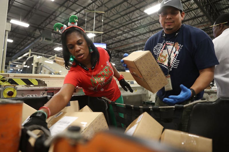 U.S. Postal service mail handlers Barbara Lynn and Daniel Diaz (R) sort boxes at the U.S. Postal service's Royal Palm Processing and Distribution Center on December 4, 2017 in Opa Locka, Florida.
