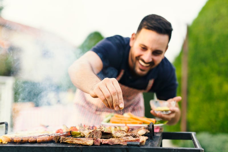 man happily seasoning his meat on the grill