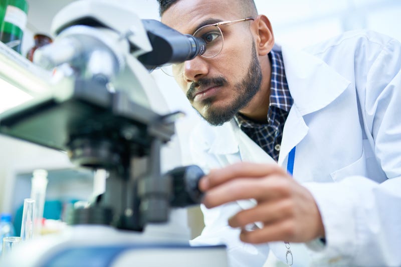 Scientist looking in microscope while working on medical research in science laboratory