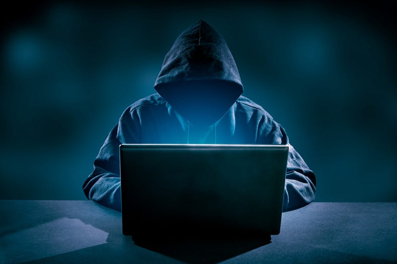 Faceless man in hood on computer